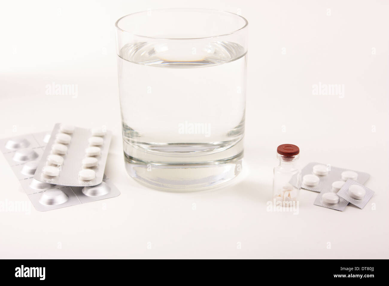 Glas mit Wasser und Tabletten, Pillen auf weißem Hintergrund Stockfoto