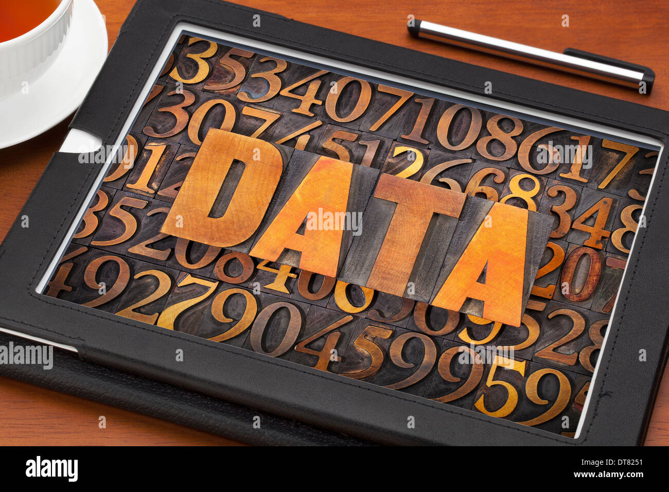 Datenwort und Zahlen in Vintage Buchdruck Holzart auf einem digitalen Tablet mit einer Tasse Tee Stockfoto
