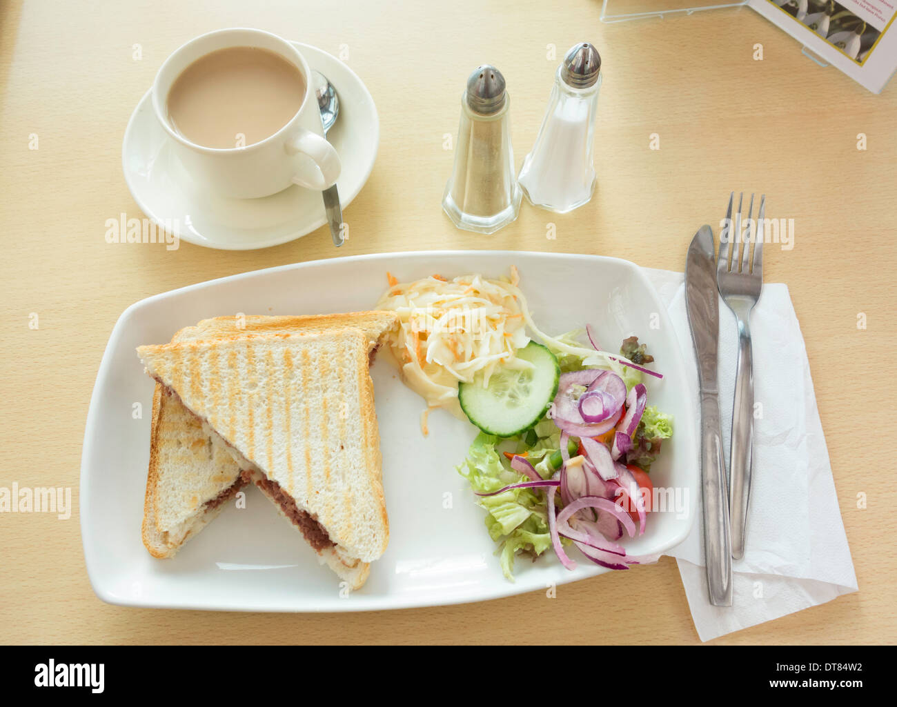 Zeit-Mittagssnack, corned ein geröstetes Rindfleisch und Zwiebeln Sandwich in Weißbrot mit Salat und Krautsalat und einer Tasse Tee Stockfoto