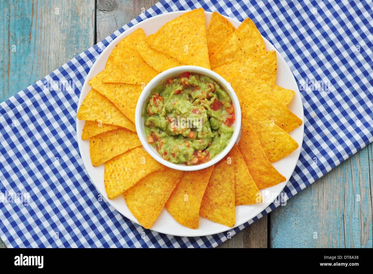 Mexikanische Guacamole Sauce mit Nachos und Tomate auf hölzernen Hintergrund Stockfoto