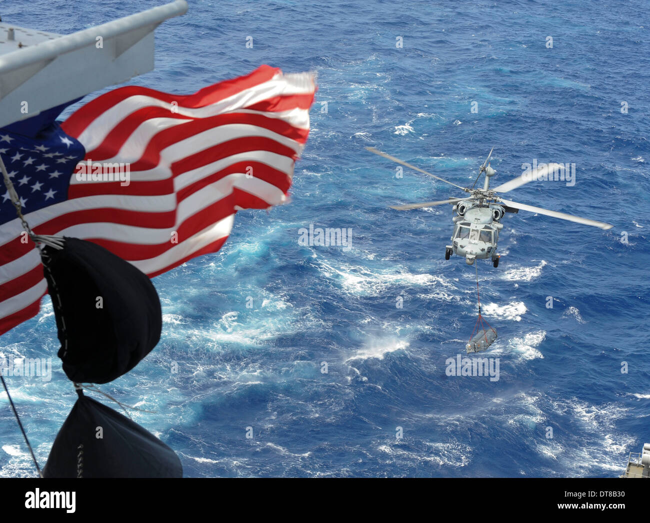 Ein MH-60 s Sea Hawk führt Lieferungen während ein Nachschub auf dem Meer. Stockfoto