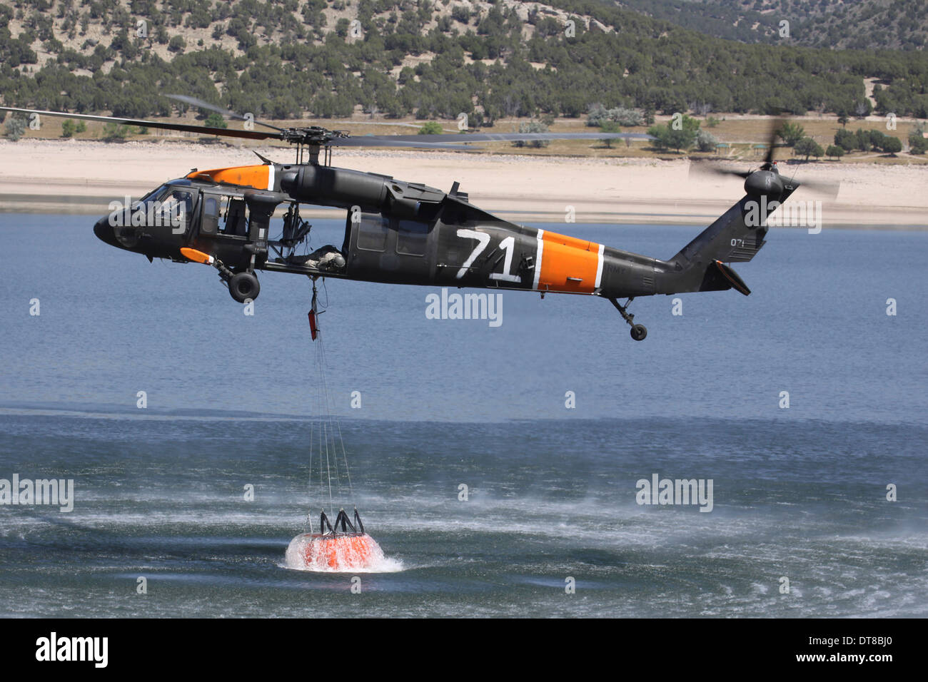 Ein US-Armee UH-60 Black Hawk Hubschrauber sammelt Wasser aus einem Reservoir. Stockfoto