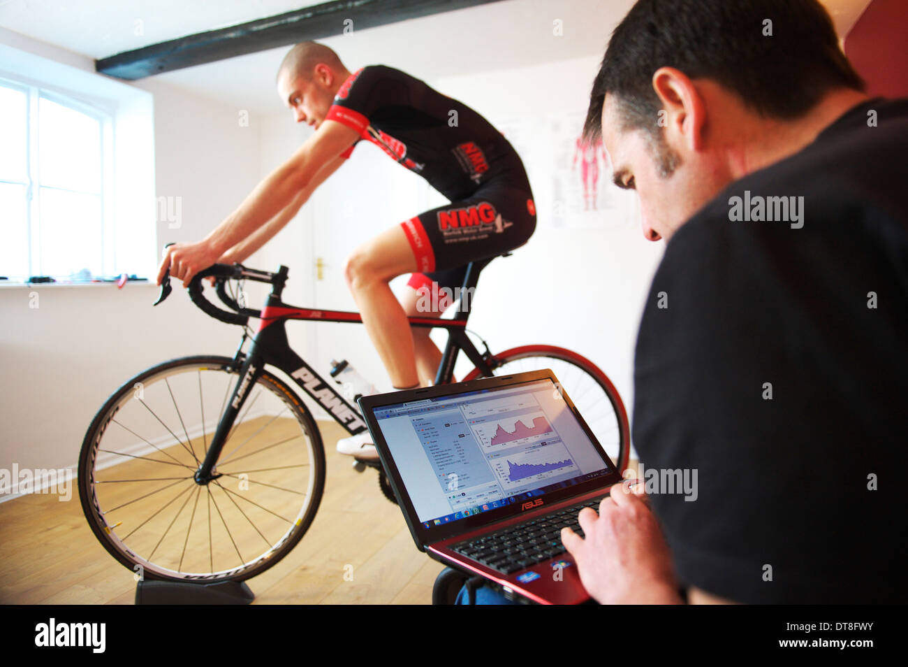 junge männliche Amateur-Radfahrer unter geht mit seinem Zyklus-Trainer testen. Stockfoto