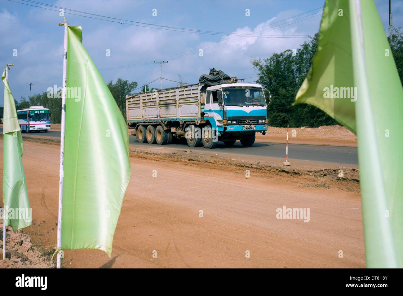 Ein grosser Lastwagen verläuft grüne Fahnen die neue Straßenbau in Kampong Cham Provinz, Kambodscha zu markieren. Stockfoto