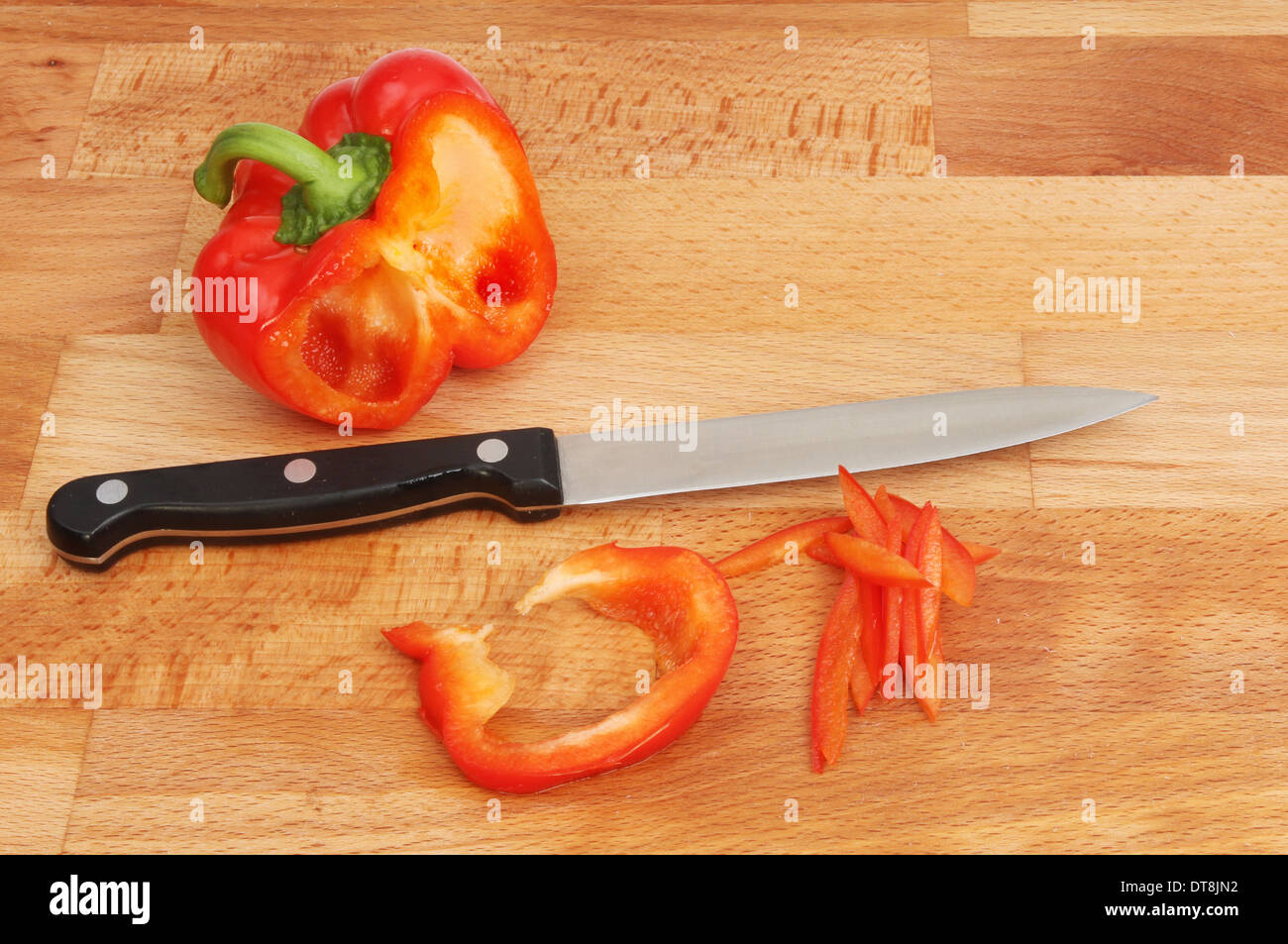 Die Hälfte der eine rote Paprika, Scheiben und Messer auf einem Buchenholz Essen Vorbereitung Brett Stockfoto