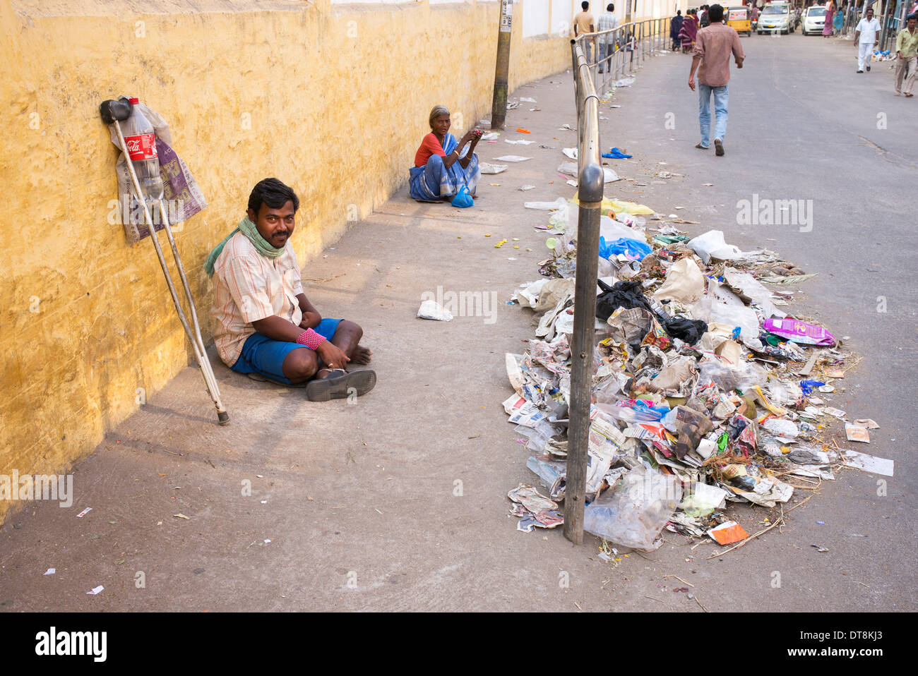 Armen behinderten Mann betteln auf eine indische Straße vor Müll. Andhra Pradesh, Indien Stockfoto