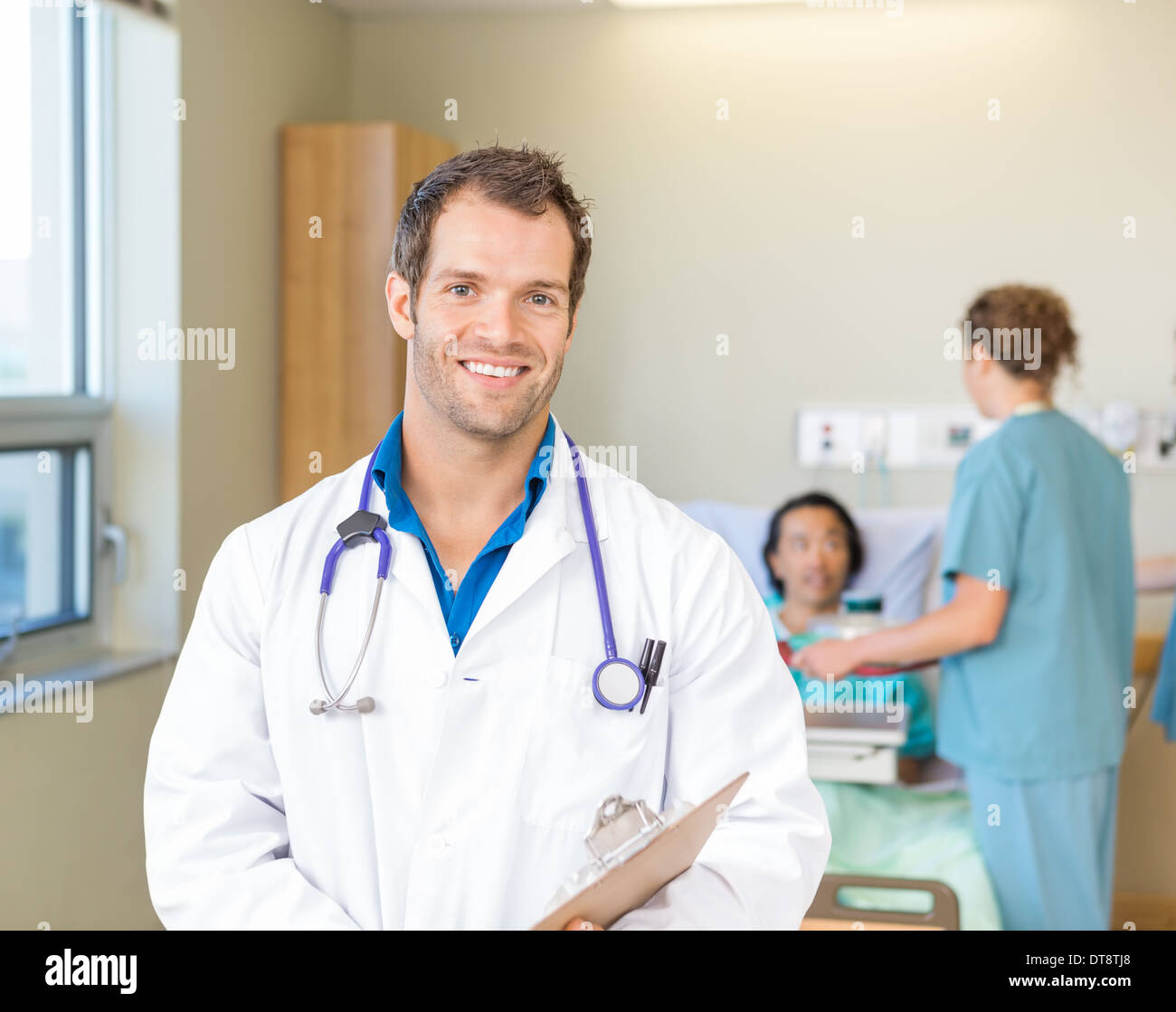 Arzt lächelnd während Krankenschwestern, die Patienten im Krankenhaus Stockfoto