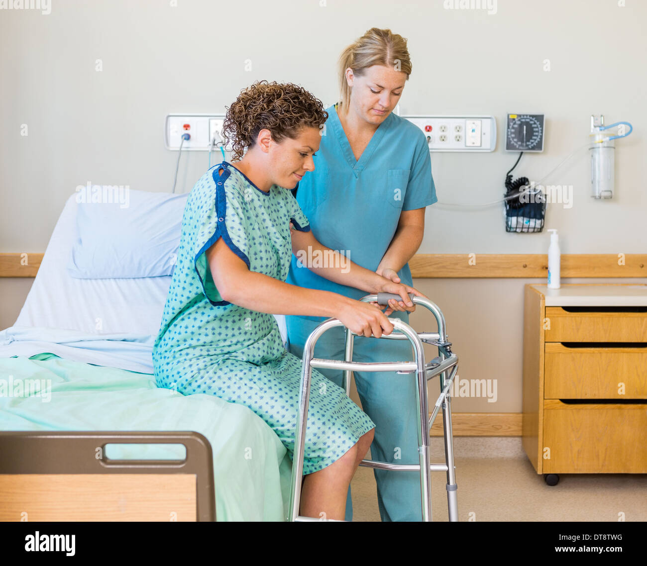 Patienten mit Walker, während Krankenschwester hilft ihr im Krankenhaus Stockfoto