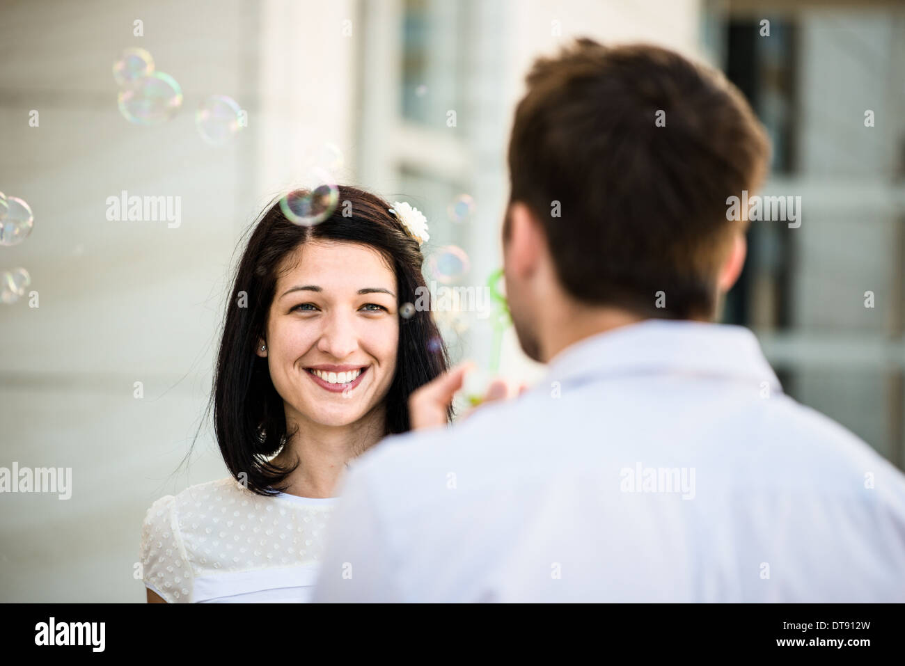 Mann bläst Seifenblasen aus Blase Gebläse auf seine Freundin - outdoor im Straße Stockfoto