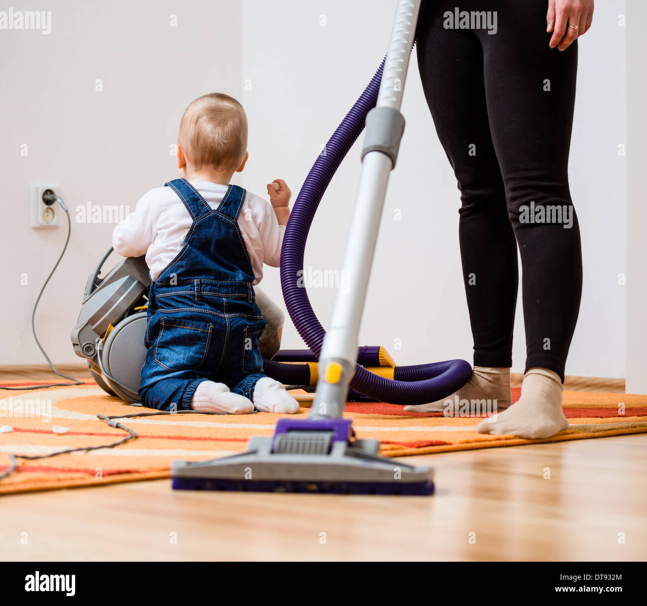 Aufräumen der Zimmer - Frau mit Staubsauger, Baby-sitting auf Etage Stockfoto