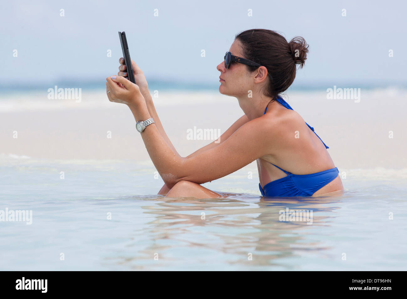 Eine Frau liest im Ozean im Urlaub Stockfoto