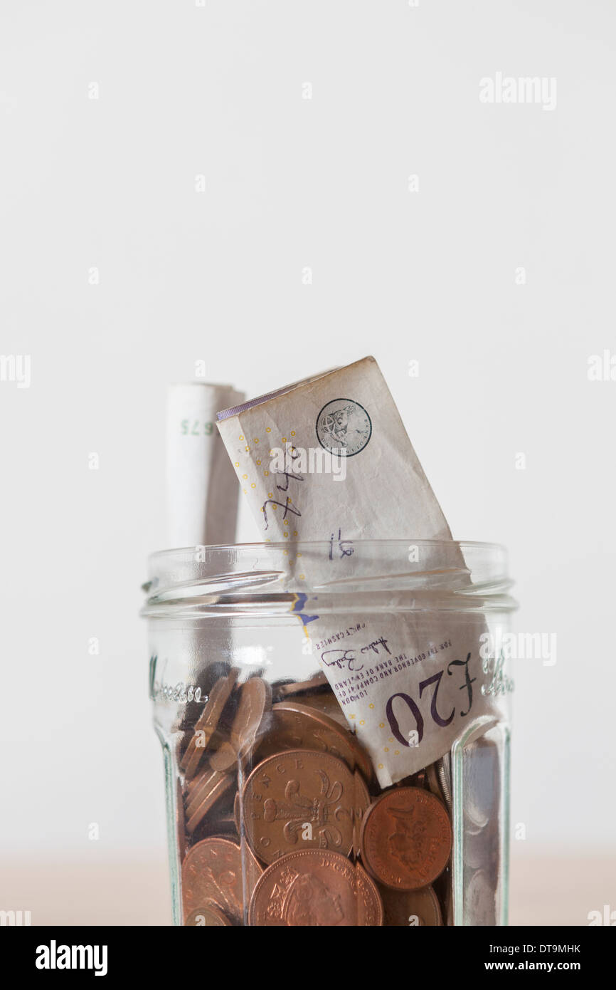 Glas mit Pfund-Banknoten und Münzen Stockfoto