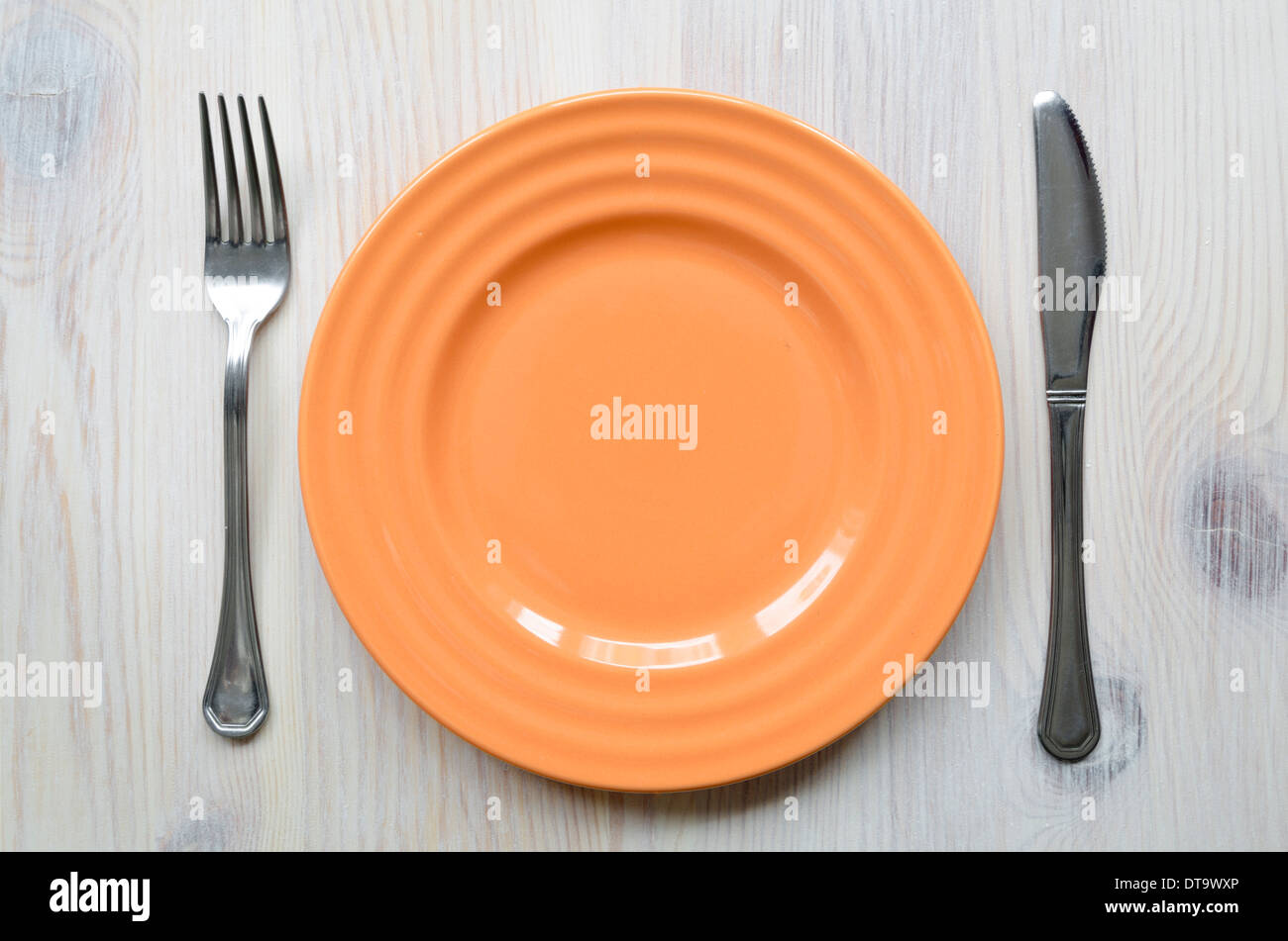 Orange leere Teller-Platte auf den hellen Holztisch mit Messer und Gabel Stockfoto