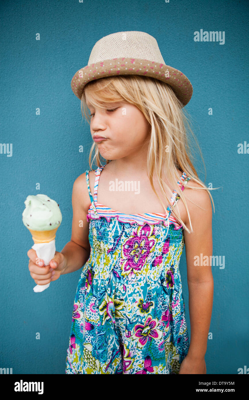 Süße junge Mädchen mit lustigen Ausdruck halten Eiswaffel außerhalb Hintergrund blaue Wand Stockfoto