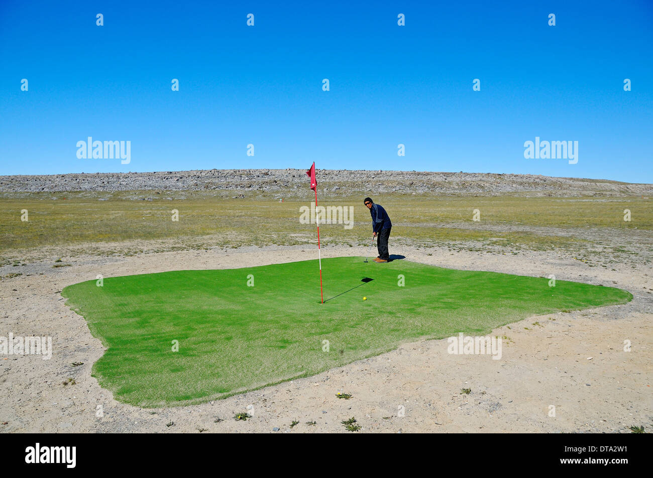 Mann schlägt einen Golfball auf dem nördlichsten Golfplatz der Welt, Victoria-Insel, früher Holman Island Stockfoto