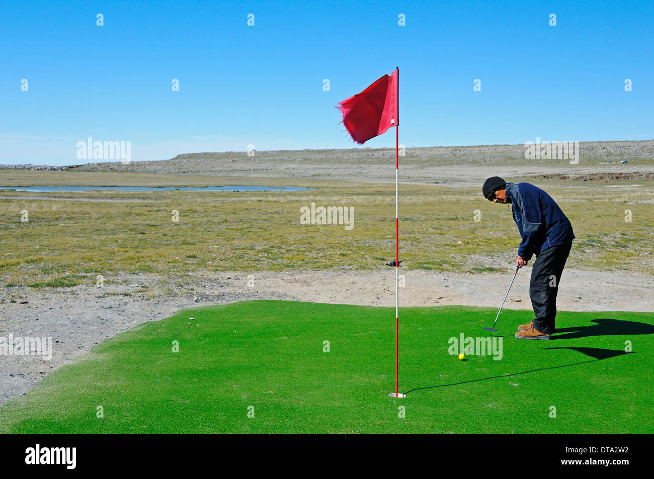 Mann schlägt einen Golfball auf dem nördlichsten Golfplatz der Welt, Victoria-Insel, früher Holman Island Stockfoto