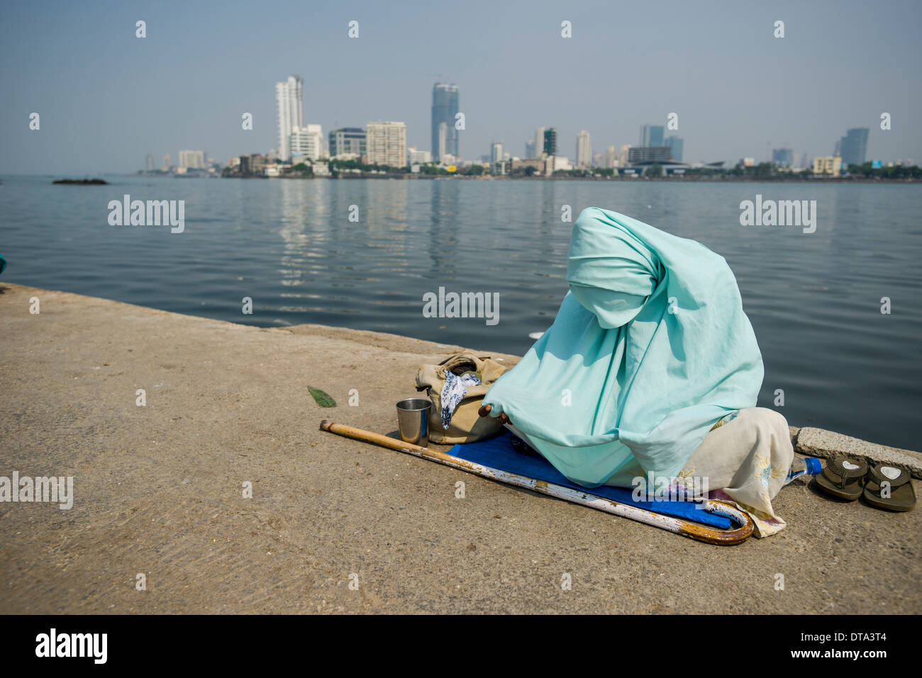 Eine muslimische Frau, die eine Burka tragen ist betteln um Geld auf dem Gehweg, Mahalaksmi, Mumbai, Maharashtra, Indien Stockfoto