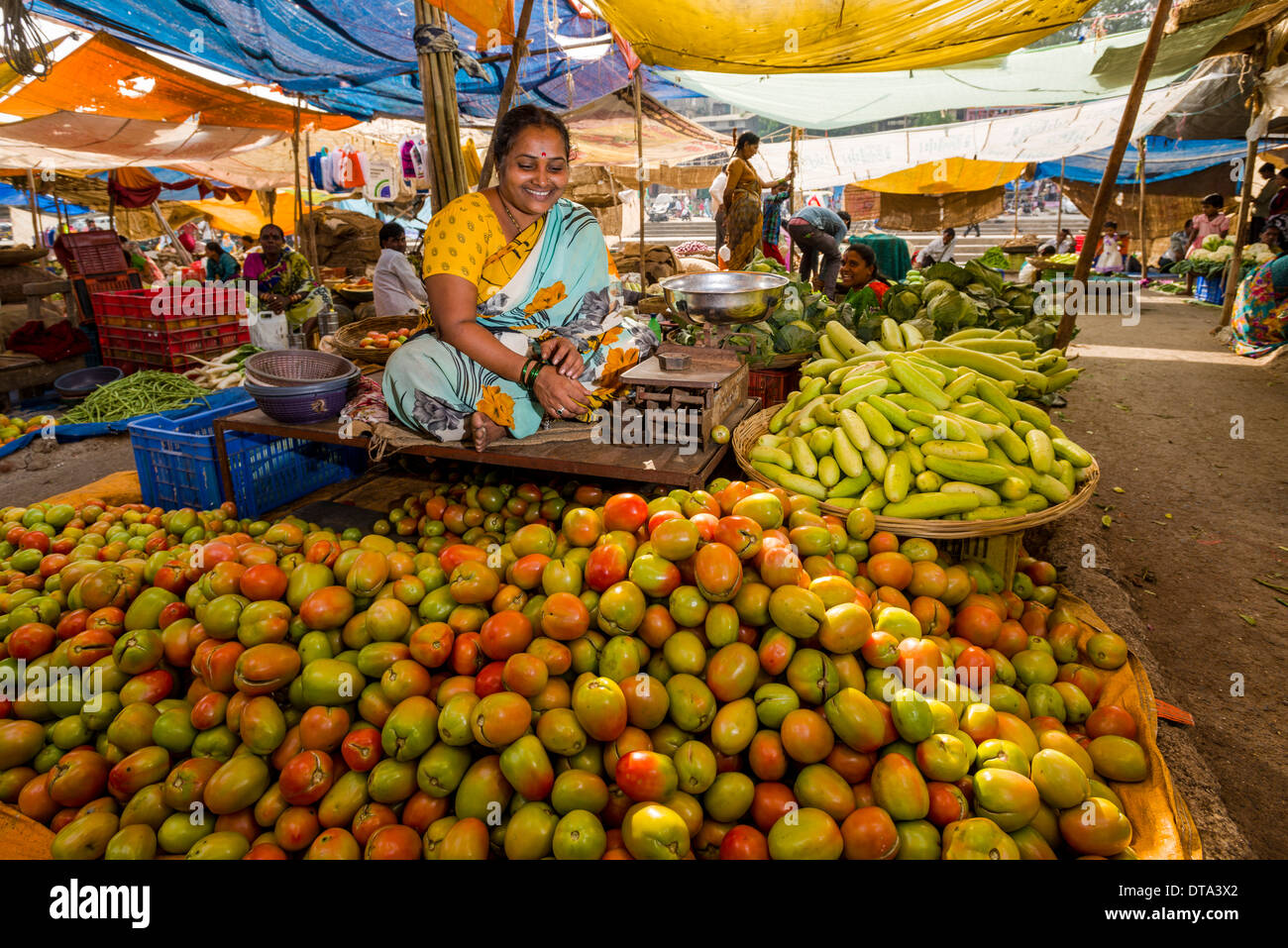 Eine Frau verkauft Tomaten und Gurken auf dem Wochenmarkt Gemüse Nasik, Maharashtra, Indien Stockfoto