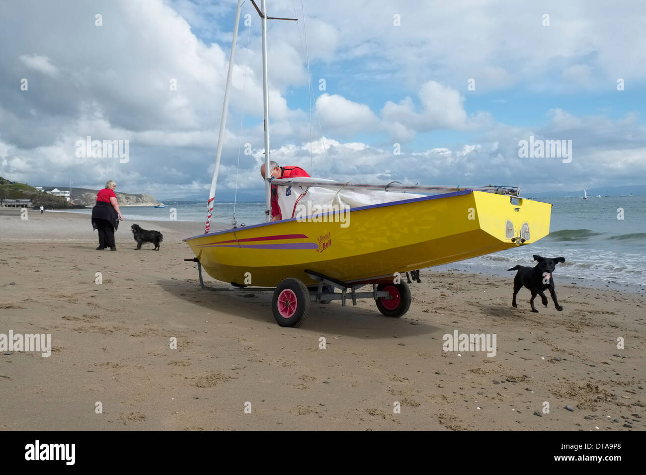 Nach dem Aftrenoon Segel: entfernen das Großsegel aus eine moderne gelbe geschälten Jolle am Strand von Abersoch, Nordwales Stockfoto