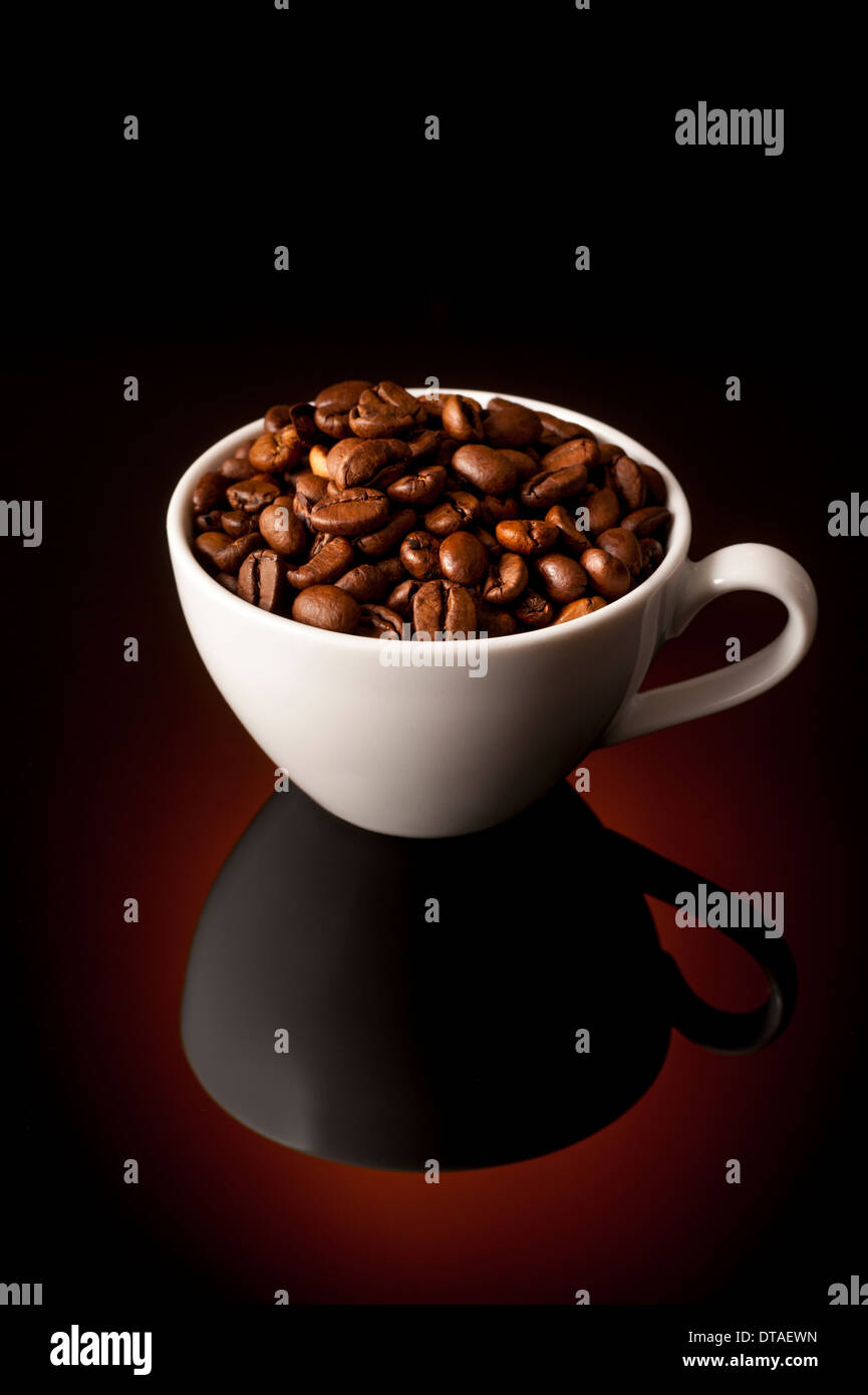 Dunkle Röstung Espresso Kaffeebohnen in kleine Espressotasse auf reflektierenden Hintergrund Stockfoto