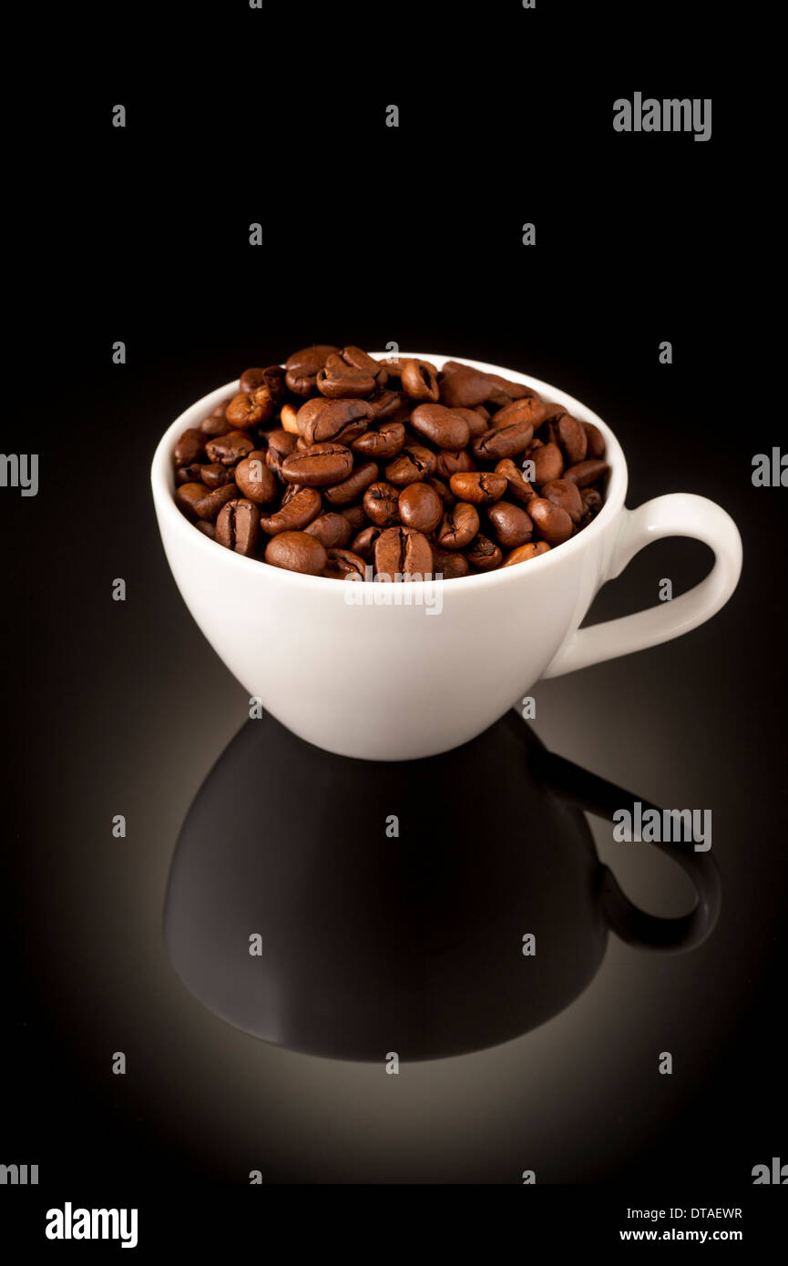 Dunkle Röstung Espresso Kaffeebohnen in kleine Espressotasse auf reflektierenden Hintergrund Stockfoto