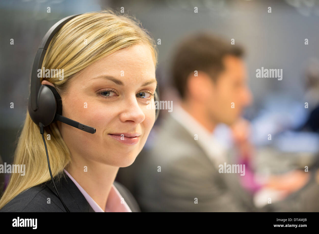Porträt der Geschäftsfrau im Büro am Telefon mit Kopfhörer, Kamera suchen Stockfoto