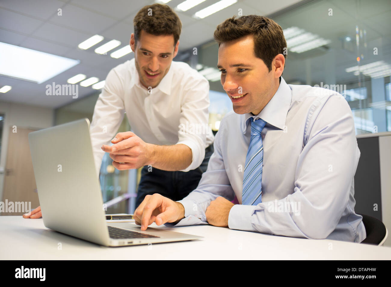 Zwei hübsche Geschäftsmann arbeiten gemeinsam an einem Laptop im Büro Stockfoto