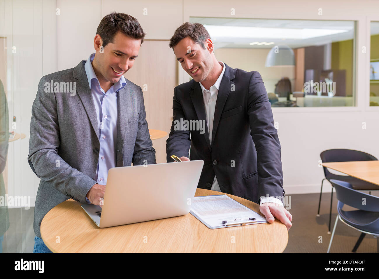 Zwei lässige Geschäftsleute arbeiten zusammen in modernen Büros mit laptop Stockfoto