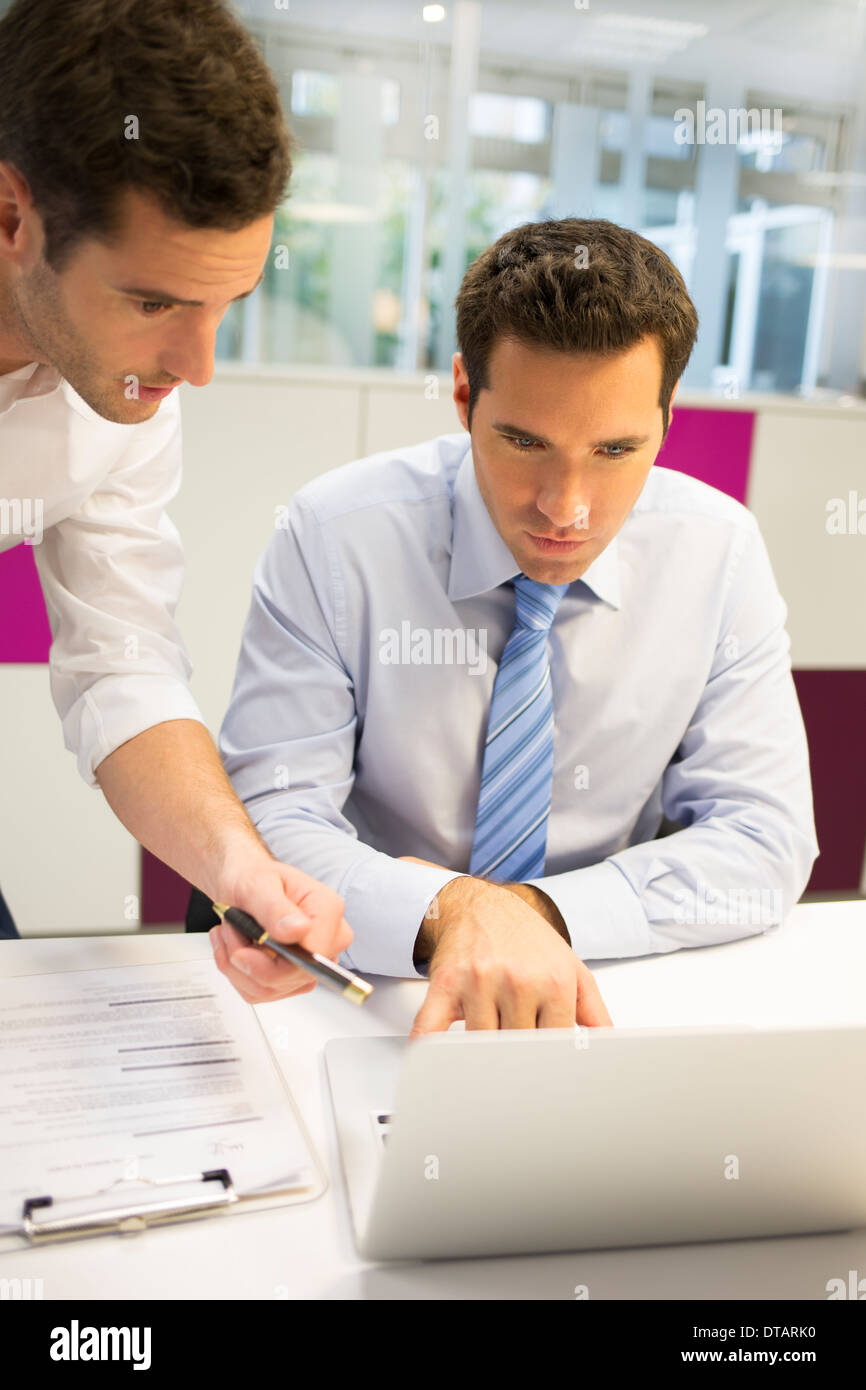 Zwei hübsche Geschäftsleute arbeiten gemeinsam an einem Laptop im Büro Stockfoto