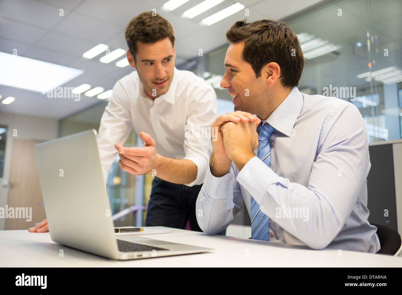 Zwei hübsche Geschäftsleute arbeiten gemeinsam an einem Laptop im Büro Stockfoto