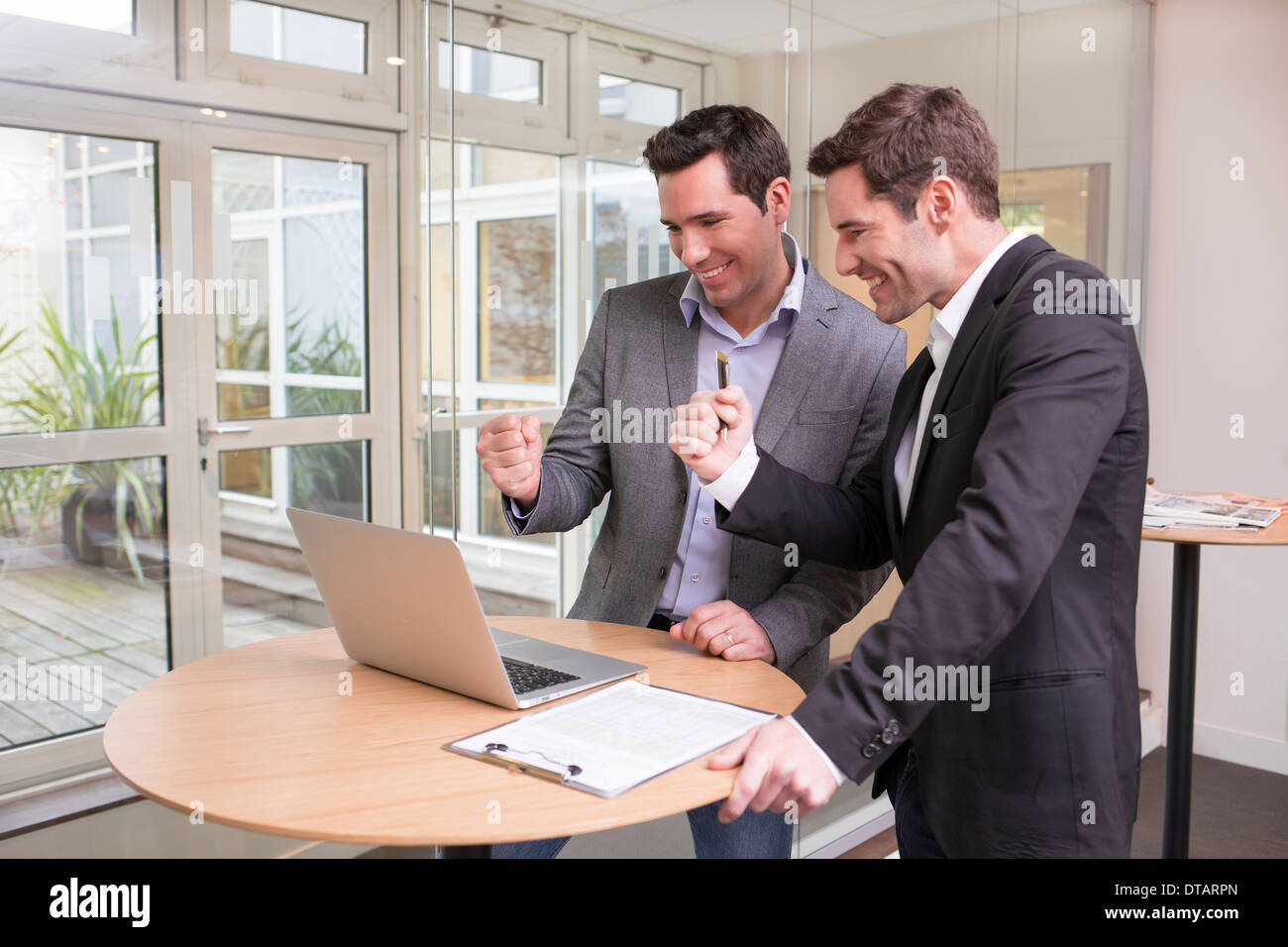 Erfolgreiche Geschäftsleute im Büro lächelnd, Daumen aufgeben Stockfoto