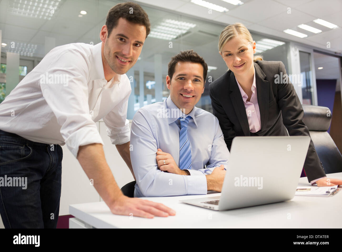 Ein Team von drei amtierenden lächelnd und Planungsarbeiten, aussehende Kamera Stockfoto