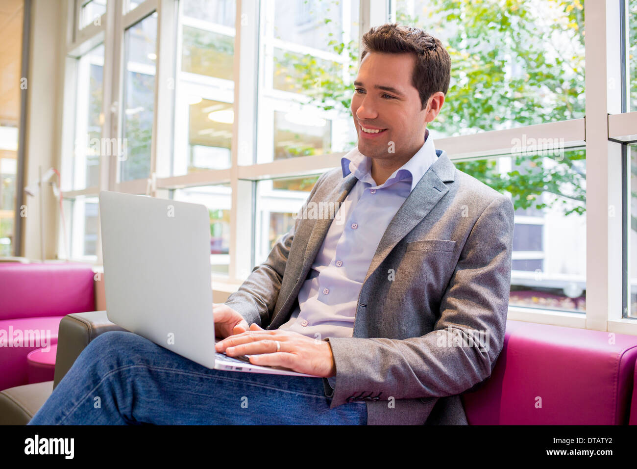 Glücklich lächelnd jungen Geschäftsmann arbeiten mit Laptop auf sofa Stockfoto