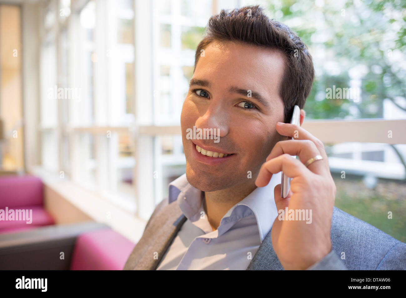 Glücklich lächelnd jungen Geschäftsmann am Telefon im Büro, auf der Kamera Suche Stockfoto