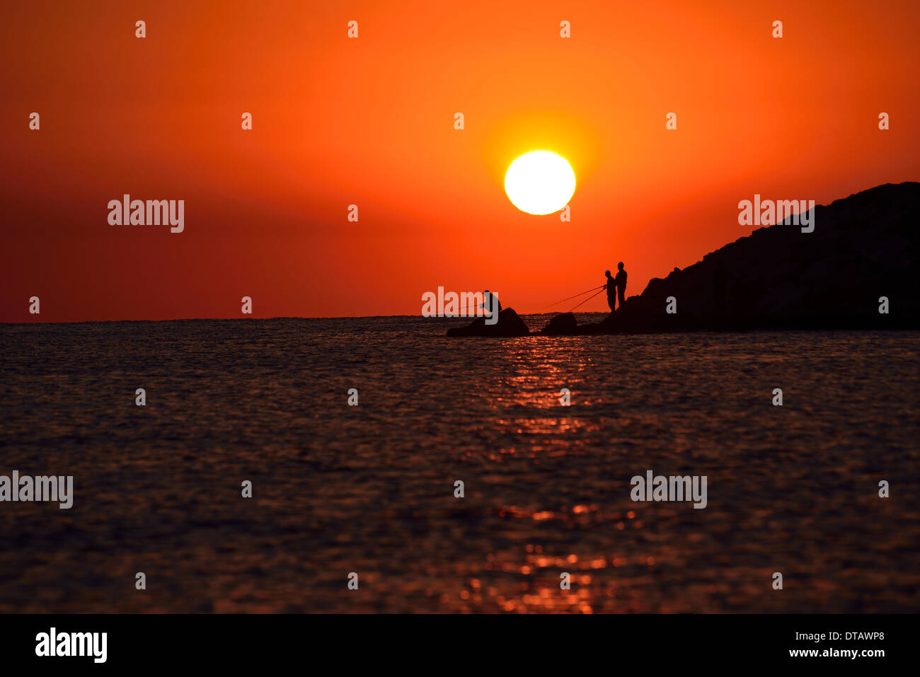 Silhouette des Mannes mit Angelrute ins Meer bei Sonnenaufgang Stockfoto