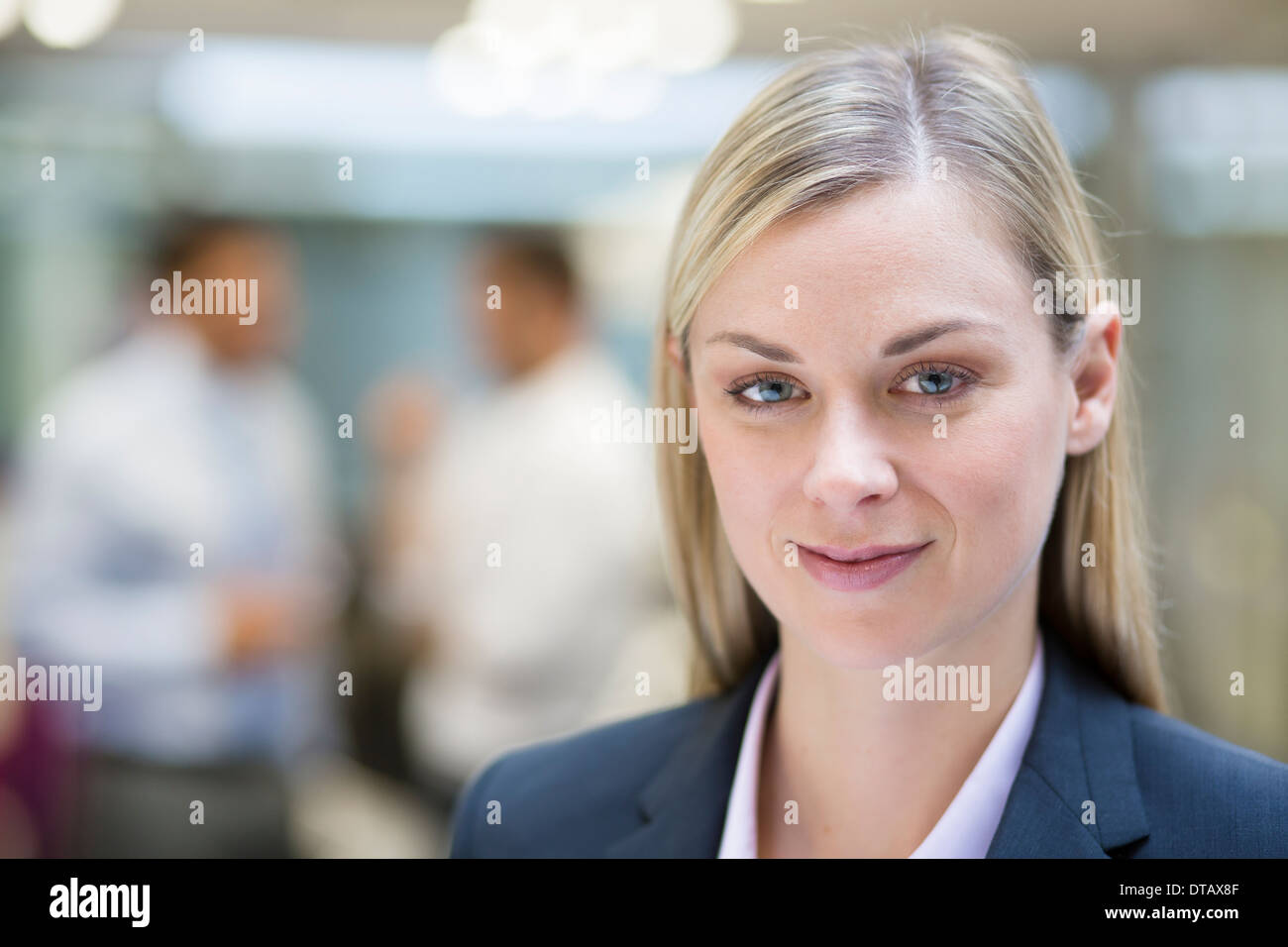 Hübsche Geschäftsfrau posiert beim Kollegen im Büro miteinander reden, auf der Kamera Suche Stockfoto