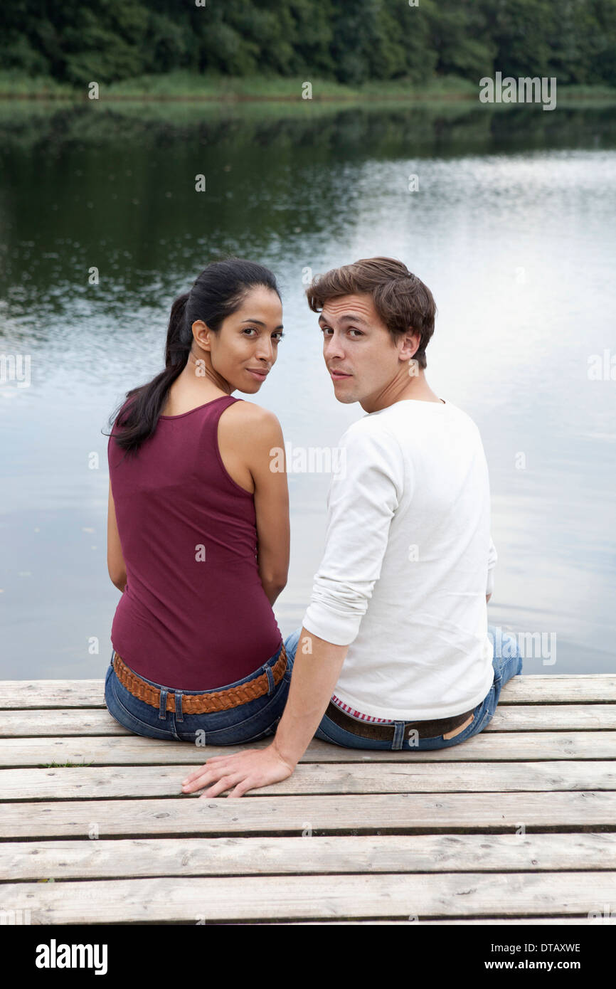 Junges Paar sitzt am Pier, über Schulter Stockfoto