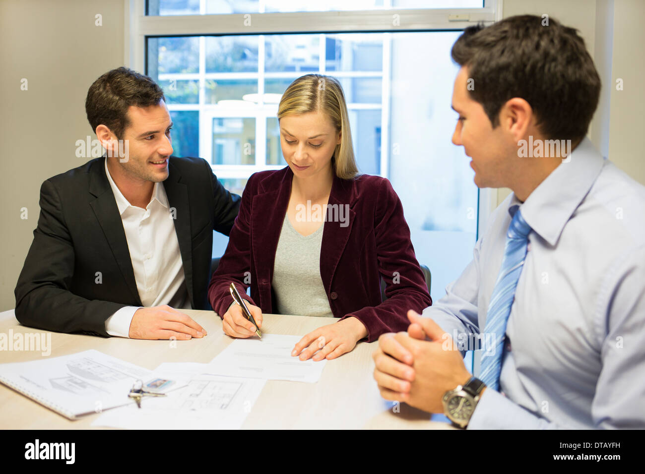 Junges Paar Vertragsunterzeichnung im Büro mit Immobilien Stockfoto