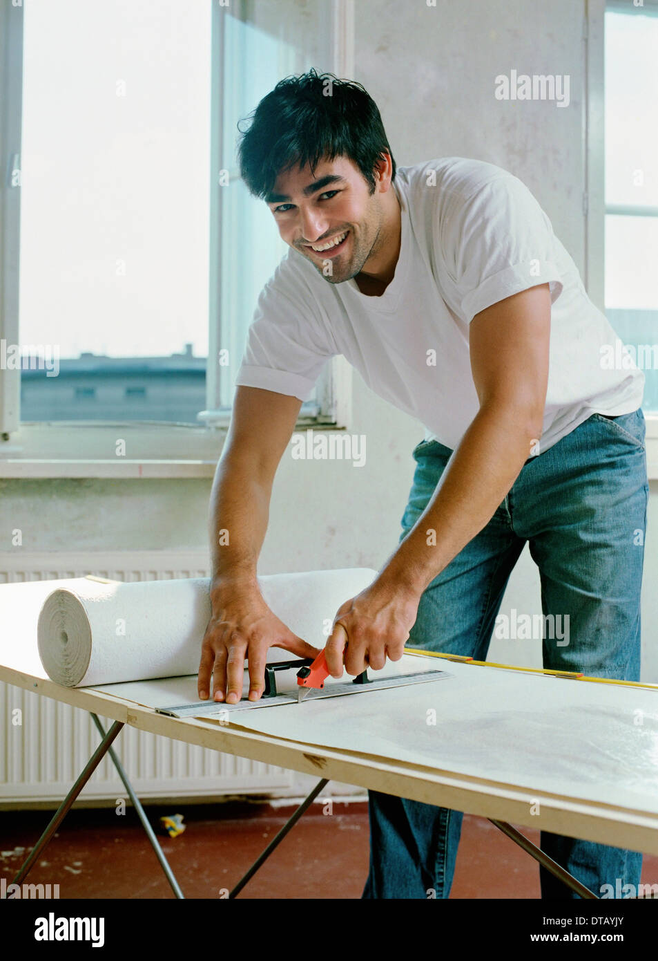 Ein Mann Schneiden von Papier mit Arbeitsgerät, Porträt Stockfoto