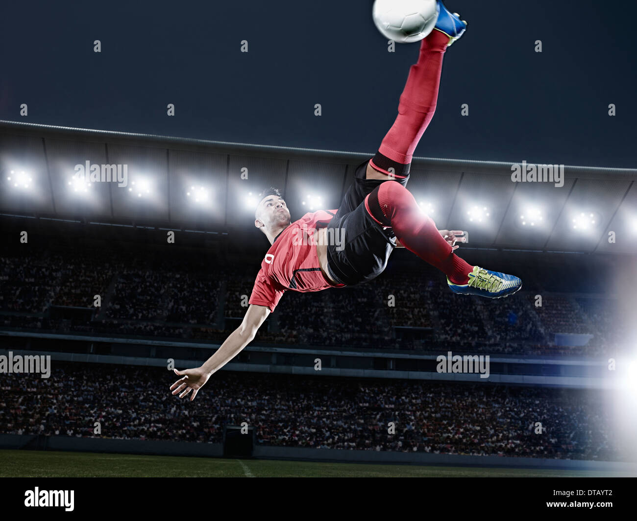 Fußball-Spieler treten Ball in der Luft auf Feld Stockfoto
