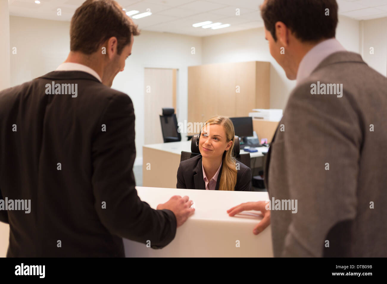 Geschäftsleute, die Kommunikation mit Frau Angestellte an der Rezeption Stockfoto