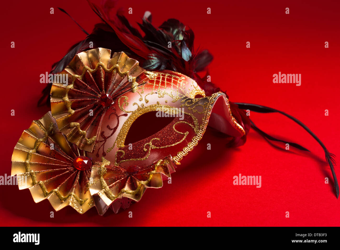 Eine rote und goldene venezianische, Karneval Maske auf rotem Grund Stockfoto