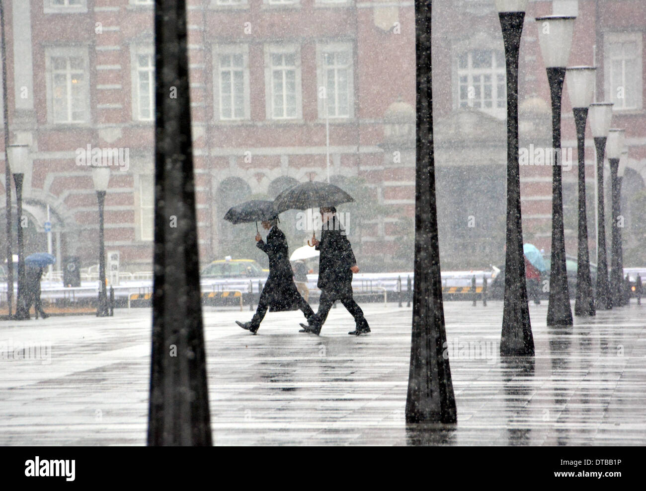 Tokio, Japan. 14. Februar 2014. Business-Leute huschen aus in den fallenden Schnee in der Nähe von Tokyo Station auf Freitag, 14. Februar 2014. Zwei Wochen in Folge, war die Hauptstadt Kanadas mit Zoll Schnee bedeckt, als eine Niederdruck Front eine breite Schneise entlang der Pazifikküste stören Land-, See- und Luft-Transport-Dienstleistungen getroffen. Bildnachweis: Natsuki Sakai/AFLO/Alamy Live-Nachrichten Stockfoto