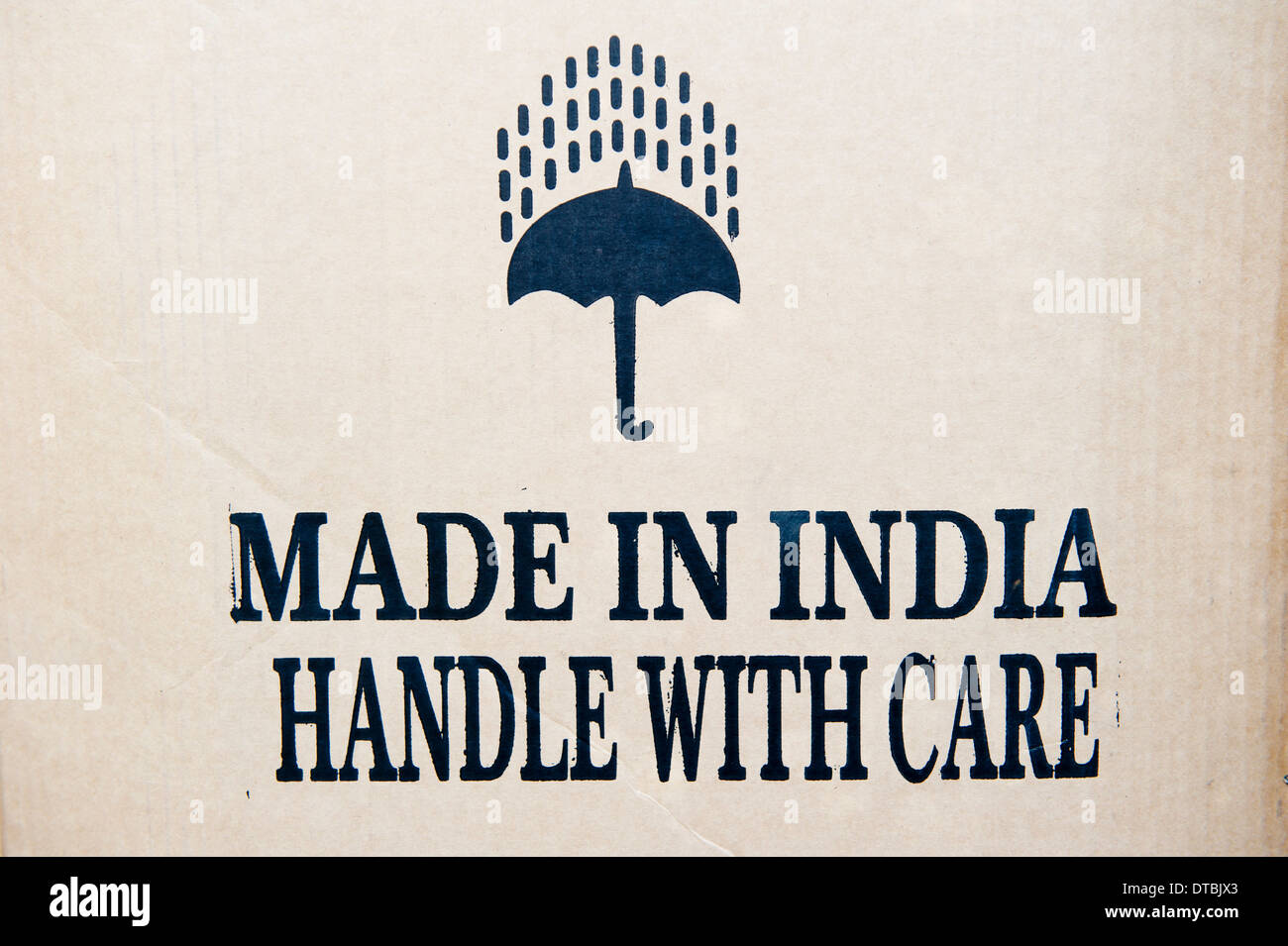 Indien, waren Box mit gedruckten Worten Made in Indien mit Vorsicht handhaben und Regenschirm mit Regen Stockfoto