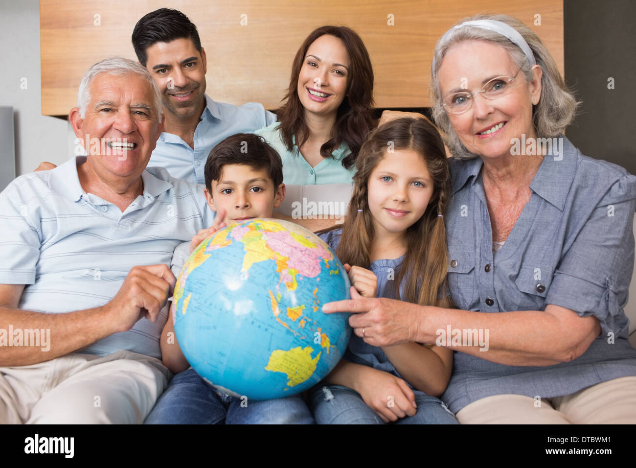 Großfamilie auf Sofa mit Globus im Wohnzimmer sitzen Stockfoto