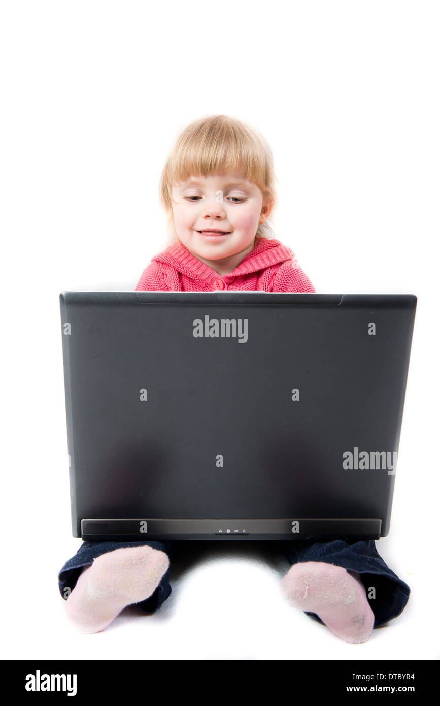 kleines Mädchen mit einem Laptop auf dem Schoß auf weißem Hintergrund Stockfoto