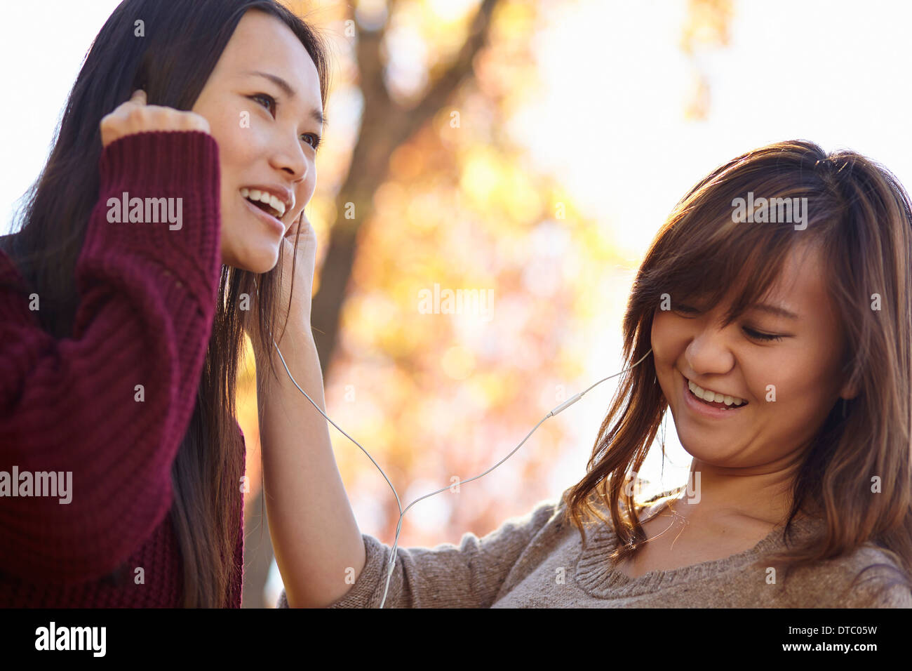 Zwei junge Frauen im Park Kopfhörer anhören Stockfoto