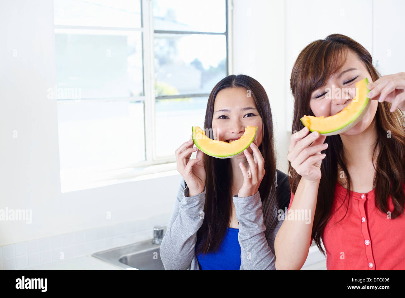 Zwei junge Frauen in der Küche mit Melone-Smiley-Gesichter Stockfoto