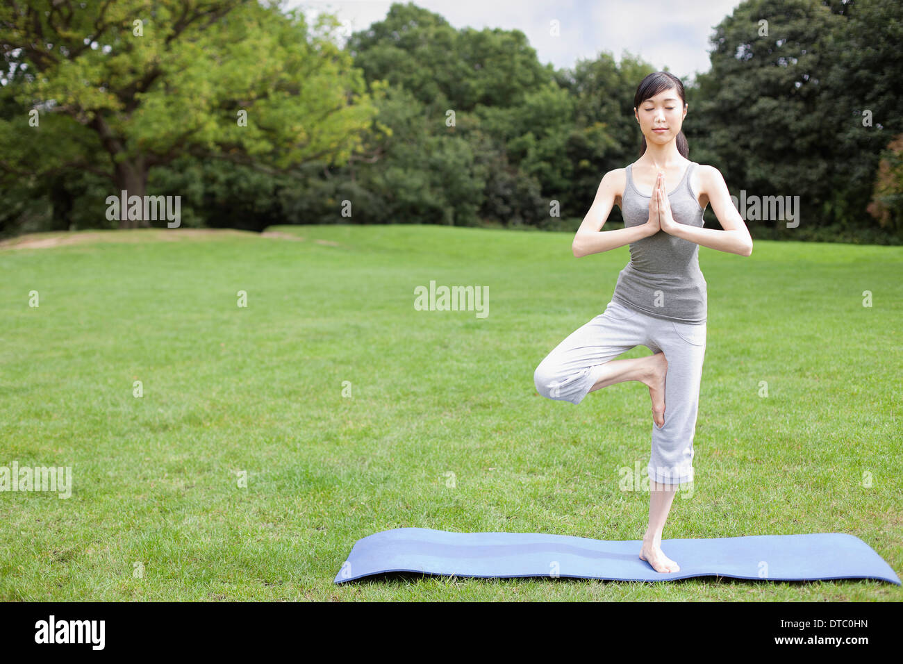 Junge Frau im Park üben Yoga-Baum-pose Stockfoto