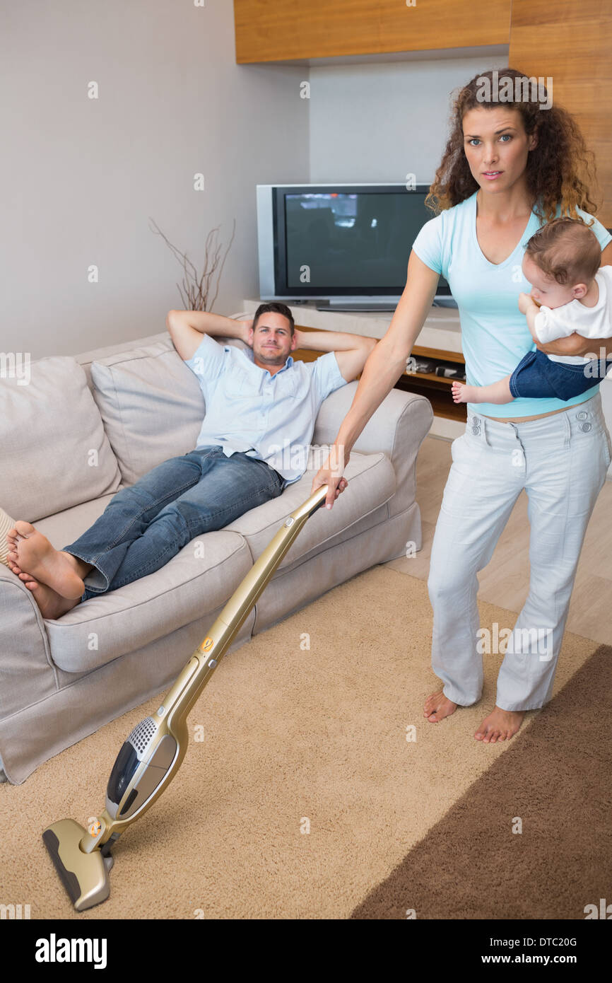 Junge Frau, die Reinigung des Hauses während des Tragens baby Stockfoto